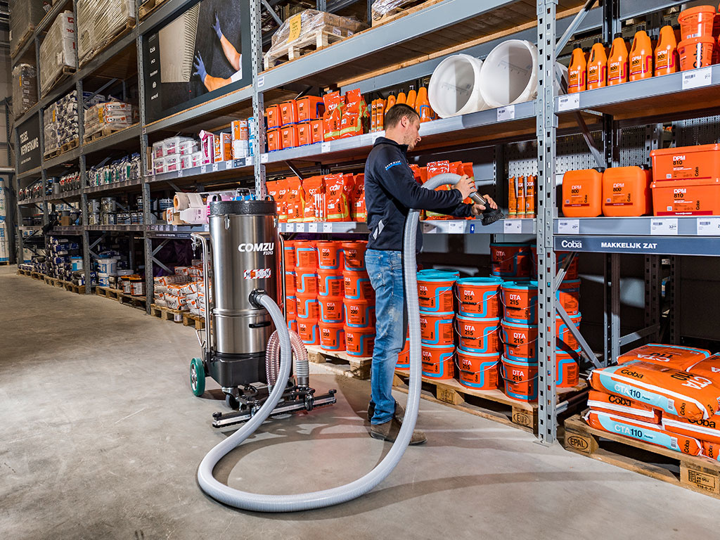 Xerowaste | Verhagen Leiden Comzu Industrial battery-powered vacuum cleaner with handheld attachment vacuuming shelves.